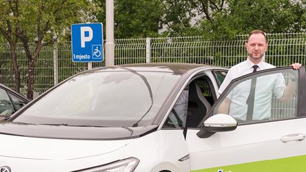 Kolega ulazi u električni automobil na parkingu